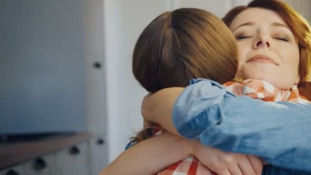 Hyvännäköinen nuori äiti halaa tytärtään tiukasti. Tytön takaosa. Muotokuva. Sulje se. Sisätilat
 - Materiaali, video