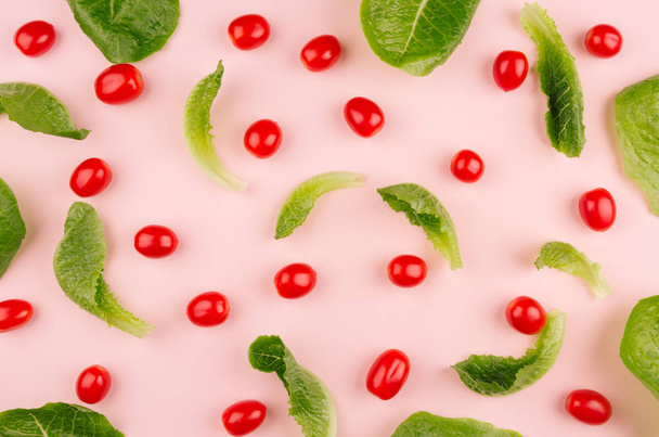 Hojas de espinacas y tomates cherry rojos sobre fondo rosa, patrón. Alimento saludable para adelgazar primavera
. - Foto, imagen