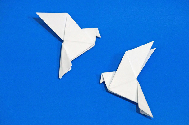 Origami περιστέρια που απομονώνονται σε μπλε φόντο. - Φωτογραφία, εικόνα