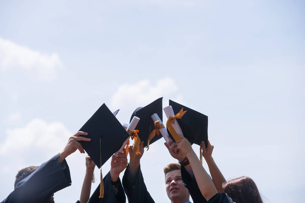 Eğitim, mezuniyet ve halk konsepti. Havan topu ve diplomalı bekarlık elbisesi giyen bir grup mutlu uluslararası öğrenci. - Fotoğraf, Görsel