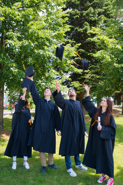 concepto de educación, graduación y personas - grupo de estudiantes internacionales felices en tablas de mortero y vestidos de soltero con diplomas - Foto, imagen