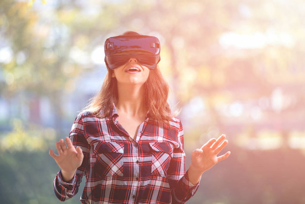 Pretty girl using VR headset outside in the park having fun - Φωτογραφία, εικόνα