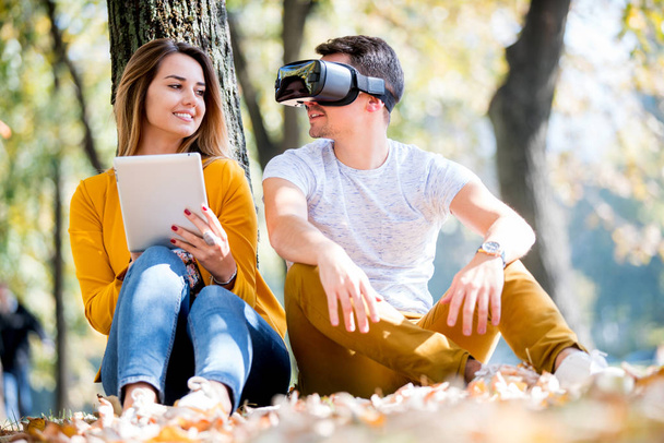 Couple sitting outside using various tech gadgets, tablet, vr, concept - Valokuva, kuva