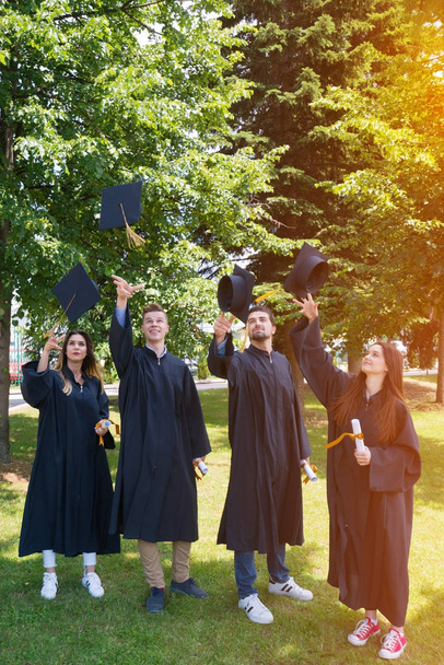 edukacja, dyplom i koncepcja ludzi - grupa szczęśliwych studentów zagranicznych w moździerzach i sukniach kawalerskich z dyplomami - Zdjęcie, obraz