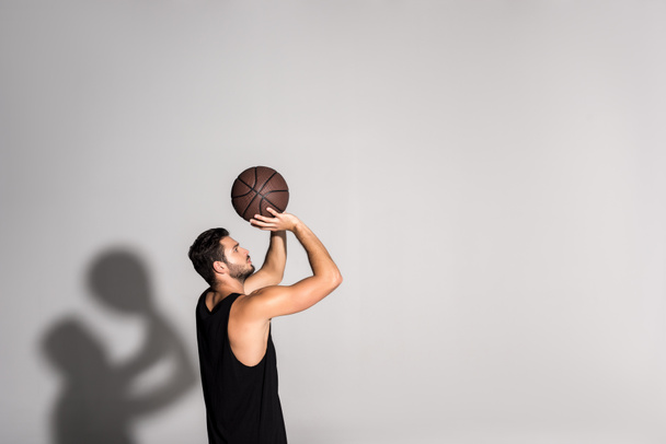 vista lateral do atlético jovem desportista jogando basquete no branco
 - Foto, Imagem