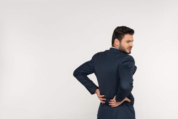 back view of young businessman suffering from backache isolated on grey - Foto, immagini