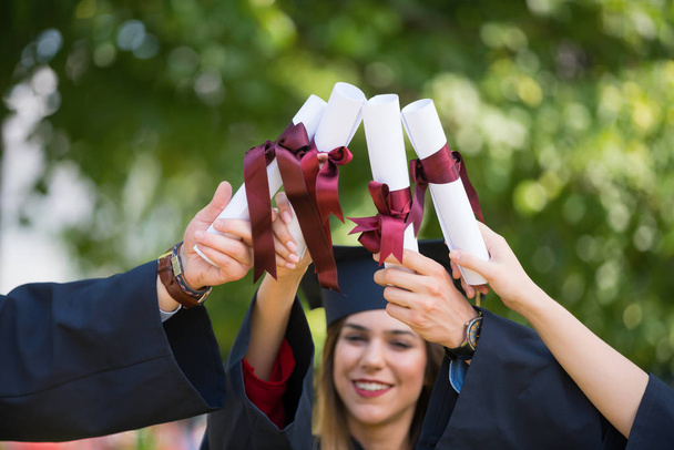 education, graduation and people concept - group of happy international students in mortar boards and bachelor gowns with diplomas - Foto, Imagen