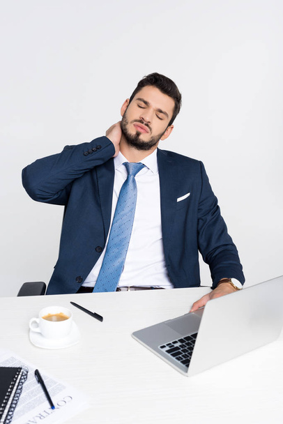 junger Geschäftsmann mit geschlossenen Augen leidet unter Nackenschmerzen im Sitzen am Arbeitsplatz   - Foto, Bild