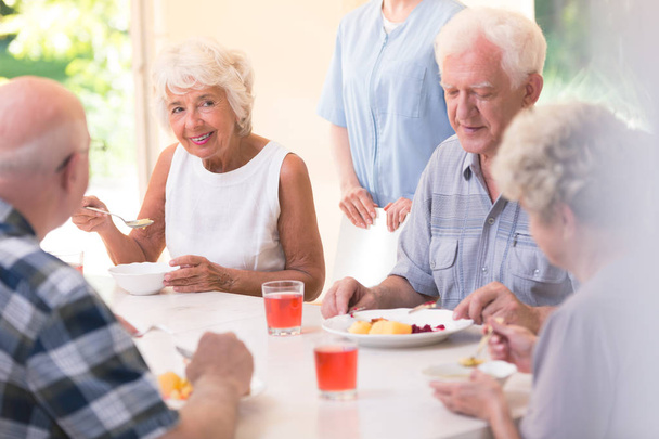 Усміхнена старша жінка їсть суп
 - Фото, зображення