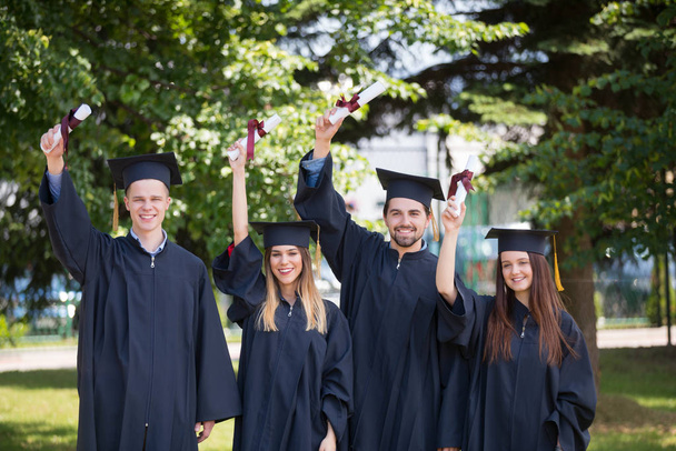 concepto de educación, graduación y personas - grupo de estudiantes internacionales felices en tablas de mortero y vestidos de soltero con diplomas - Foto, imagen