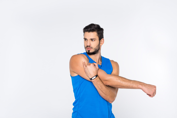 handsome sporty man stretching hands and looking away isolated on white   - Photo, Image