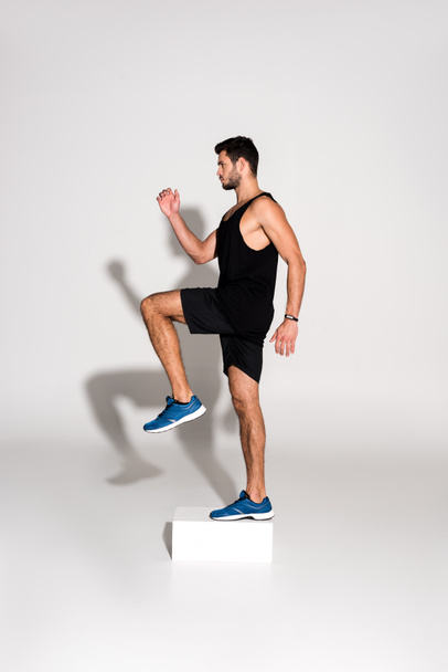 side view of sportive man doing step aerobics on block - Photo, Image