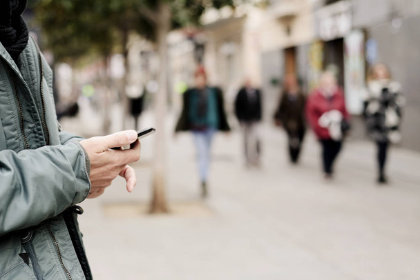 νεαρός άνδρας χρησιμοποιώντας ένα smartphone στο δρόμο - Φωτογραφία, εικόνα