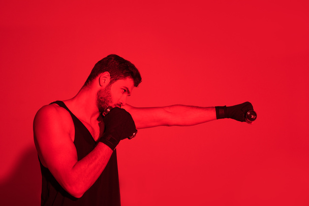 visão lateral de lutador fazendo sucesso com as mãos cobertas com ligaduras sob luz vermelha
 - Foto, Imagem