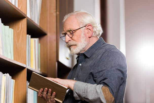 graue Haare Bibliothekarin liest Buch - Foto, Bild