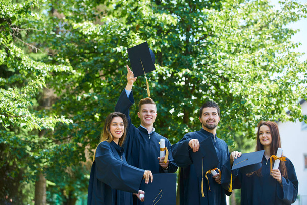 education, graduation and people concept - group of happy international students in mortar boards and bachelor gowns with diplomas - Φωτογραφία, εικόνα