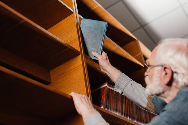 bibliotecario capelli grigi prendendo libro dallo scaffale
 - Foto, immagini