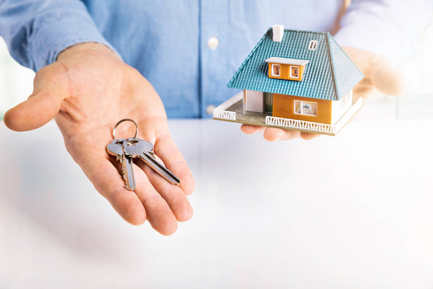 Immobilienmakler mit Hausmodell und Schlüssel in der Hand - Foto, Bild