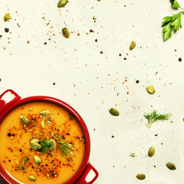 Spicy pumpkin soup puree with spices, herbs and pumpkin seeds in serving pots, gray background, top view - Zdjęcie, obraz