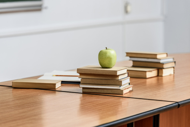 ripe apple on stack of books on table in lecture room - Фото, изображение