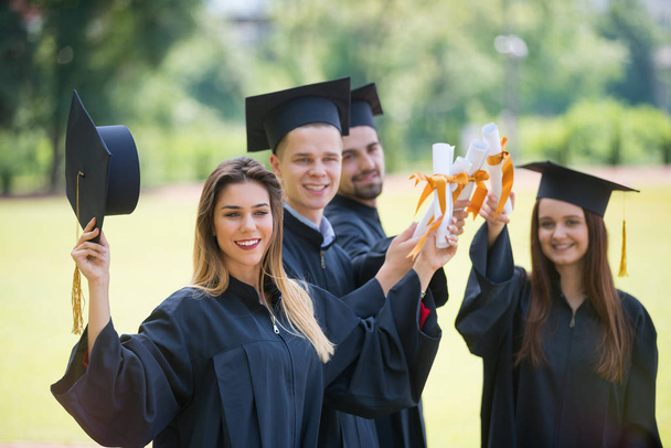 onderwijs, afstuderen en mensen concept - groep gelukkige internationale studenten in mortierbesturen en bachelor jurken met diploma 's - Foto, afbeelding