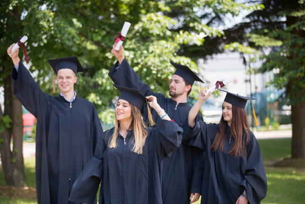 concepto de educación, graduación y personas - grupo de estudiantes internacionales felices en tablas de mortero y vestidos de soltero con diplomas - Foto, Imagen