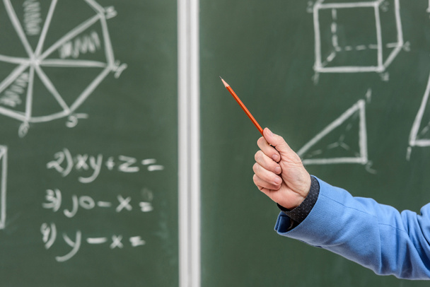 cropped image of senior professor pointing on something with pencil on blackboard - Zdjęcie, obraz