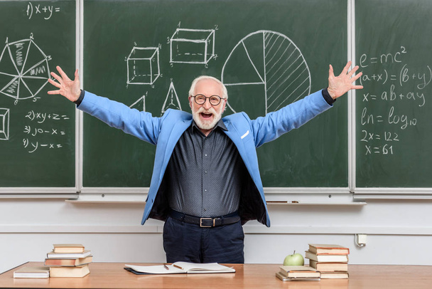счастливый старший преподаватель с распростертыми объятиями стоит у доски
 - Фото, изображение
