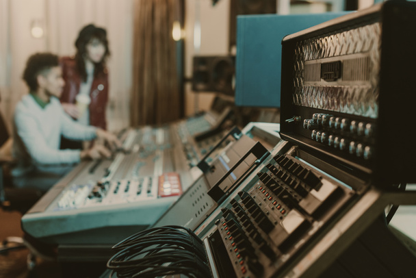 γκρο πλαν βολή του ήχου ενισχυτές στο στούντιο ηχογράφησης με θολή παραγωγούς πίσω από - Φωτογραφία, εικόνα