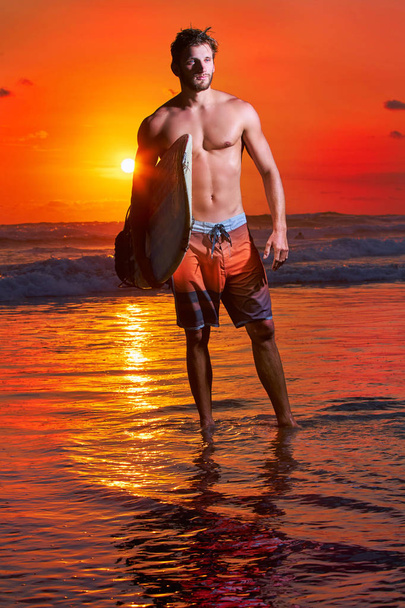 Surfer on the ocean beach at sunset on Bali island, Indonesia - Photo, image