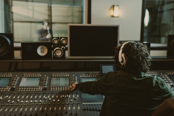 back view do produtor de som trabalhando em estúdio durante a gravação da música
 - Foto, Imagem