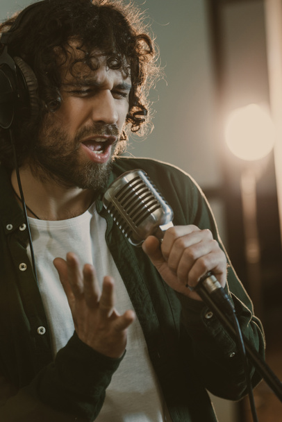 emotional young singer in headphone performing song at studio - Foto, Bild