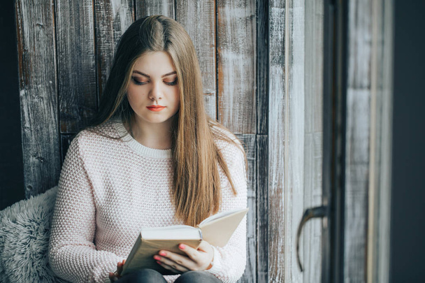 Kaunis tyttö lukee kirjaa, kodin ja mukavuuden käsitteitä
 - Valokuva, kuva