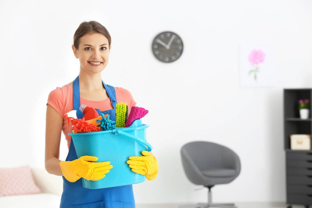 Young woman with cleaning supplies in flat - Foto, Imagen