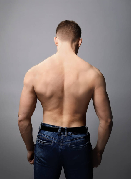 Muscular young bodybuilder on grey background - Foto, Imagen