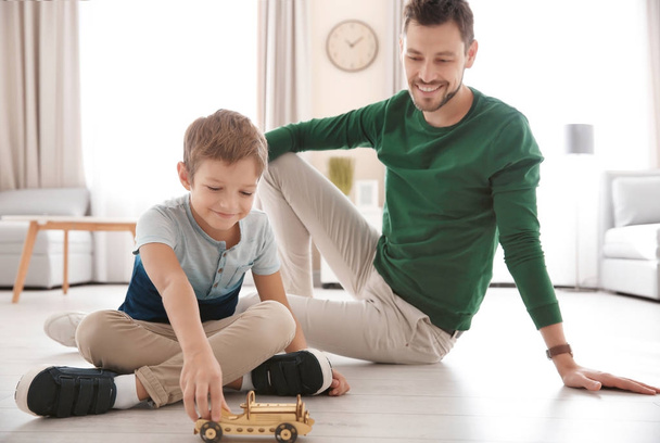 Söpö pieni poika ja isä leikkivät leluautolla lattialla kotona - Valokuva, kuva