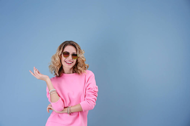 Attractive young woman with heart shaped sunglasses on color background - Foto, Imagen