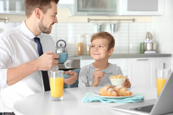 Father with son having breakfast in kitchen - Фото, изображение