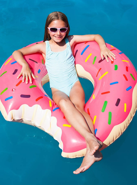 Mädchen liegt auf einem bunten aufblasbaren Donut  - Foto, Bild