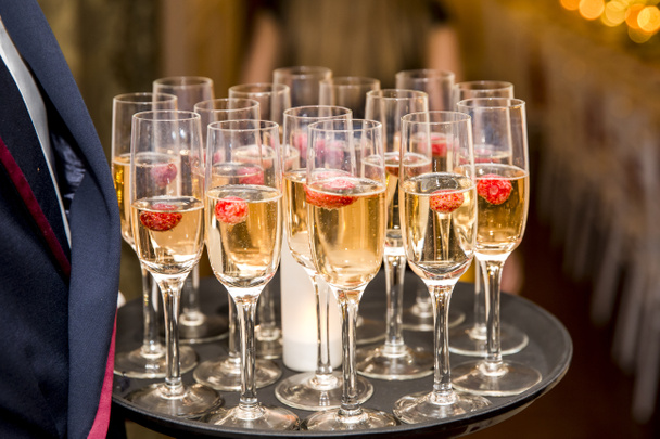 Waiter served champagne glasses on a tray in a fine dining resta - 写真・画像
