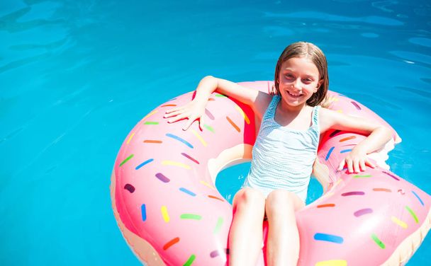 Girl laying on a colorful inflatable donut  - Zdjęcie, obraz