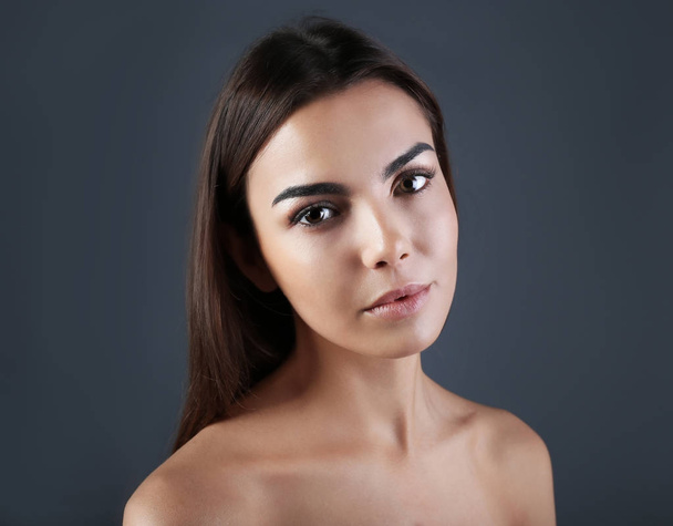 Beautiful young woman with eyelash extensions on grey background - Фото, зображення