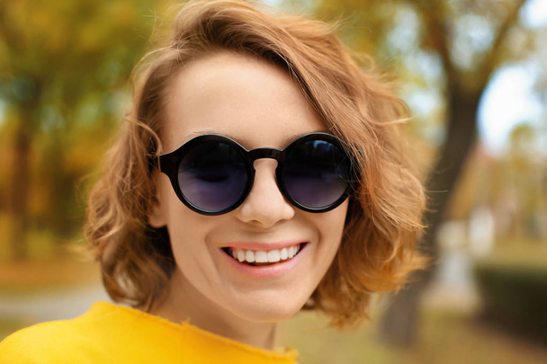 Beautiful smiling woman in bright yellow sweatshirt outdoors - Zdjęcie, obraz