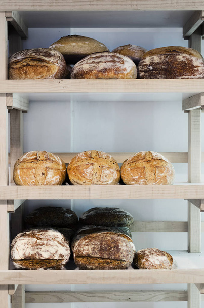 Variety of delicious breads displayed on shelves in bakery - Photo, Image