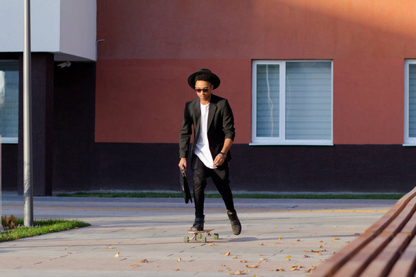 Concept of young,fast and mobile manager. Funny buisinessman on skateboard in black suit. - Foto, Imagen