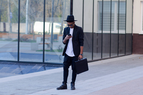 young happy male in black suit and black hat, concept of modern buisinessman - Foto, imagen