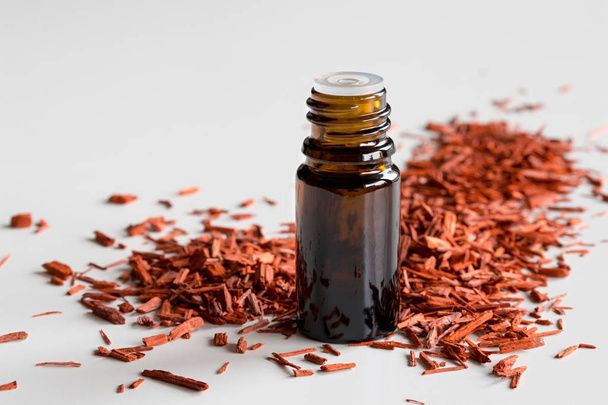 A bottle of sandalwood essential oil with sandalwood - Photo, Image