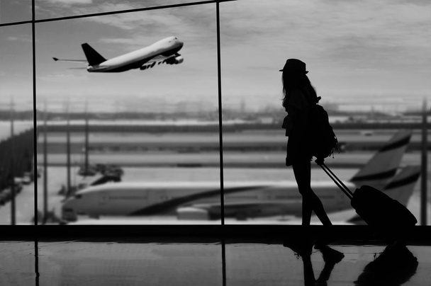 Mladá žena stojí u okna na letišti a sledování  - Fotografie, Obrázek