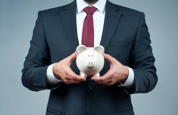 Finance Savings concept. Businessman in suit is holding piggy bank.  - Foto, afbeelding