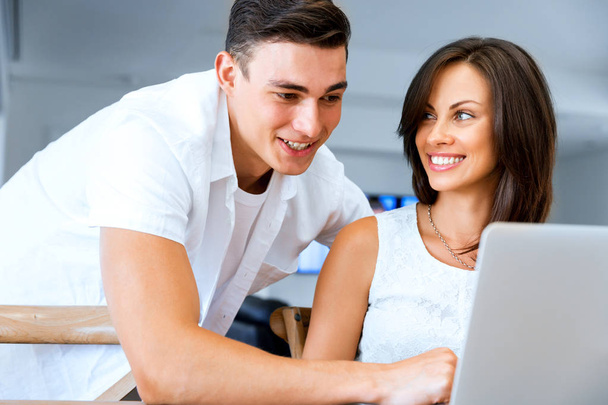 Happy modern couple working on laptop at home - Фото, изображение